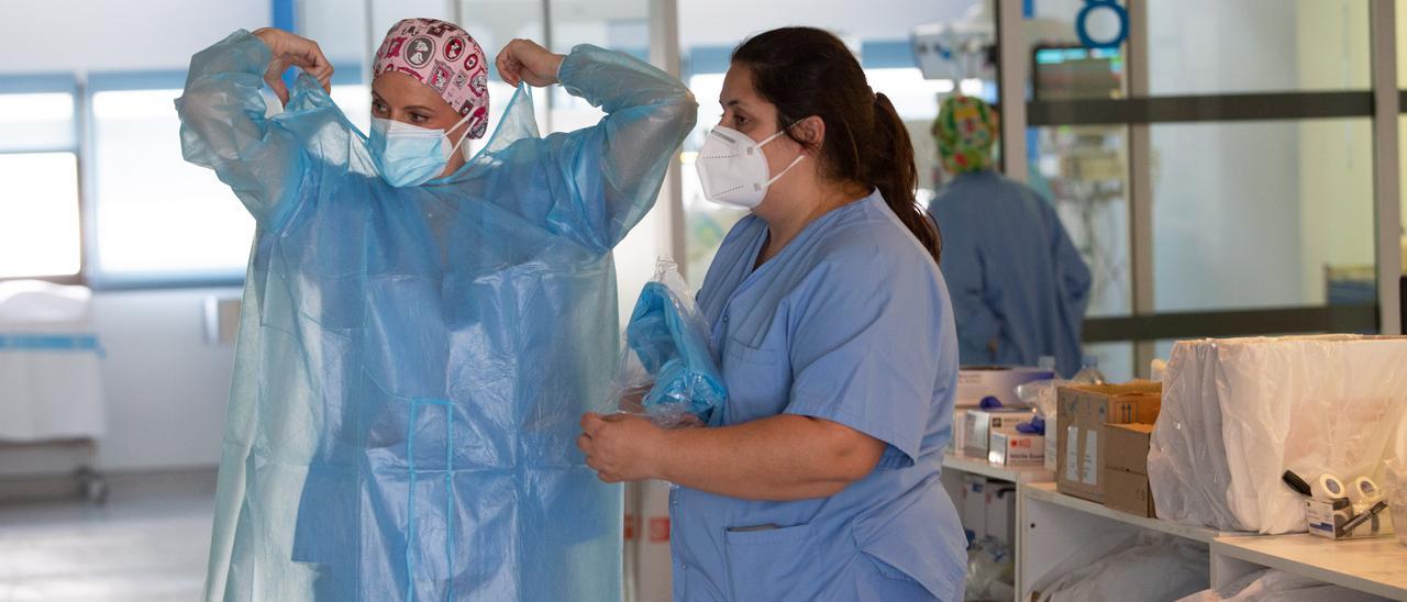 Una profesional sanitaria de la UCI del hospital Can Misses se pone el equipamiento de protección.