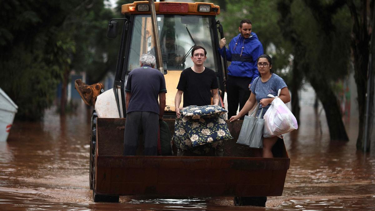 Tres personas son evacuadas en una excavadora de una zona inundada de Porto Alegre.
