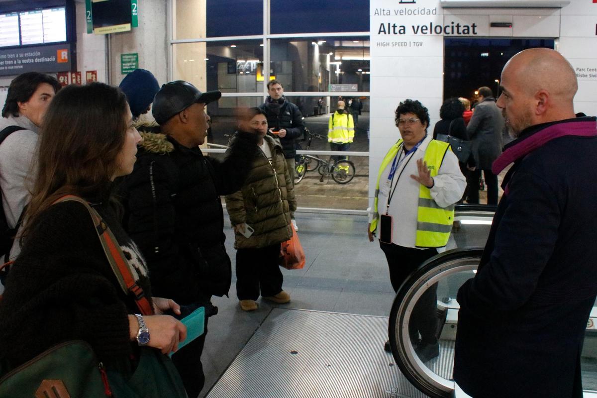 Una informadora a l'estació de trens de Girona explicant als usuaris la suspensió de Rodalies.