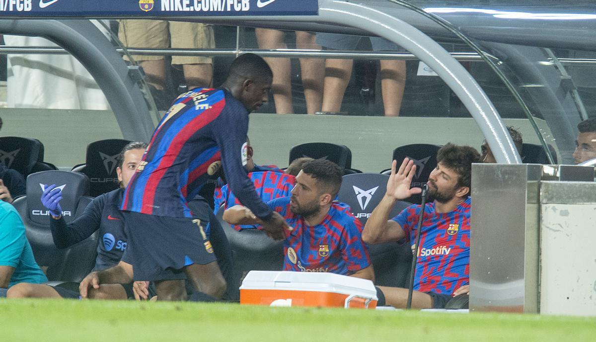 Dembelé saluda a sus compañeros de banquillo, Alba y Piqué, tras ser sustituído.