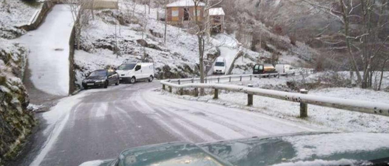 Varios coches, aparcados en la carretera para evitar recorrer la calzada, cubierta de hielo.