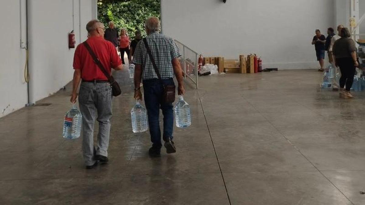 Dos vecinos abandonan el recinto ferial de Tarazona con garrafas de agua, la semana pasada.