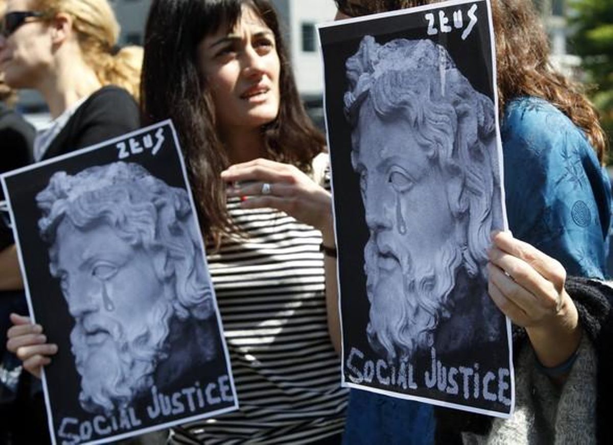 Una dona sosté pancartes al·lusives a la crisi grega davant la seu de la UE a Bèlgica.