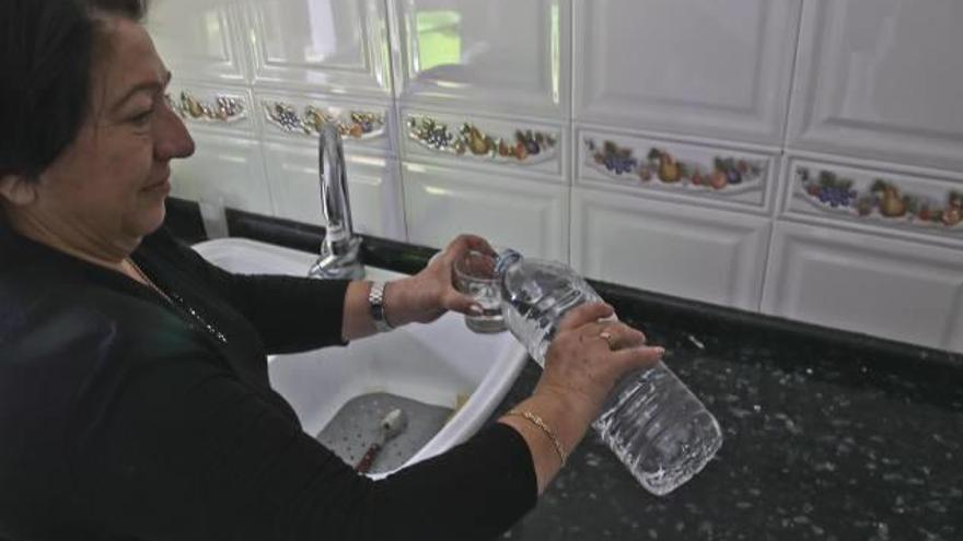 Una vecina de l&#039;Alcúdia sirviendo un vaso de agua embotellada al no poder consumir la del grifo.