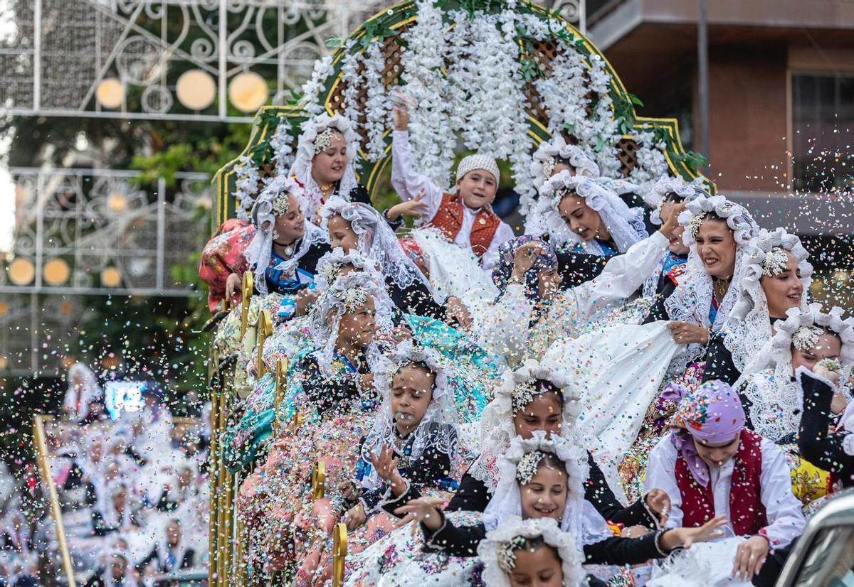 Varios participantes, en su mayoría niños, lanzando confeti desde una de las carrozas.