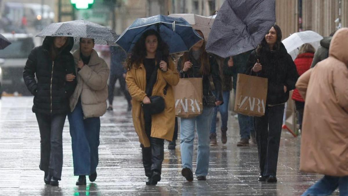 Varias jóvenes pasean bajo la lluvia este miércoles en Vigo.