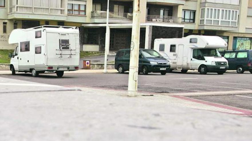 Autocaravanas y furgonetas aparcadas en Salinas delante del edificio «Gauzón I».