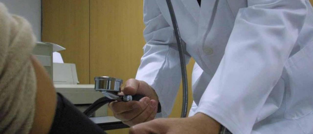 Un médico mide la tensión a un paciente en consulta.