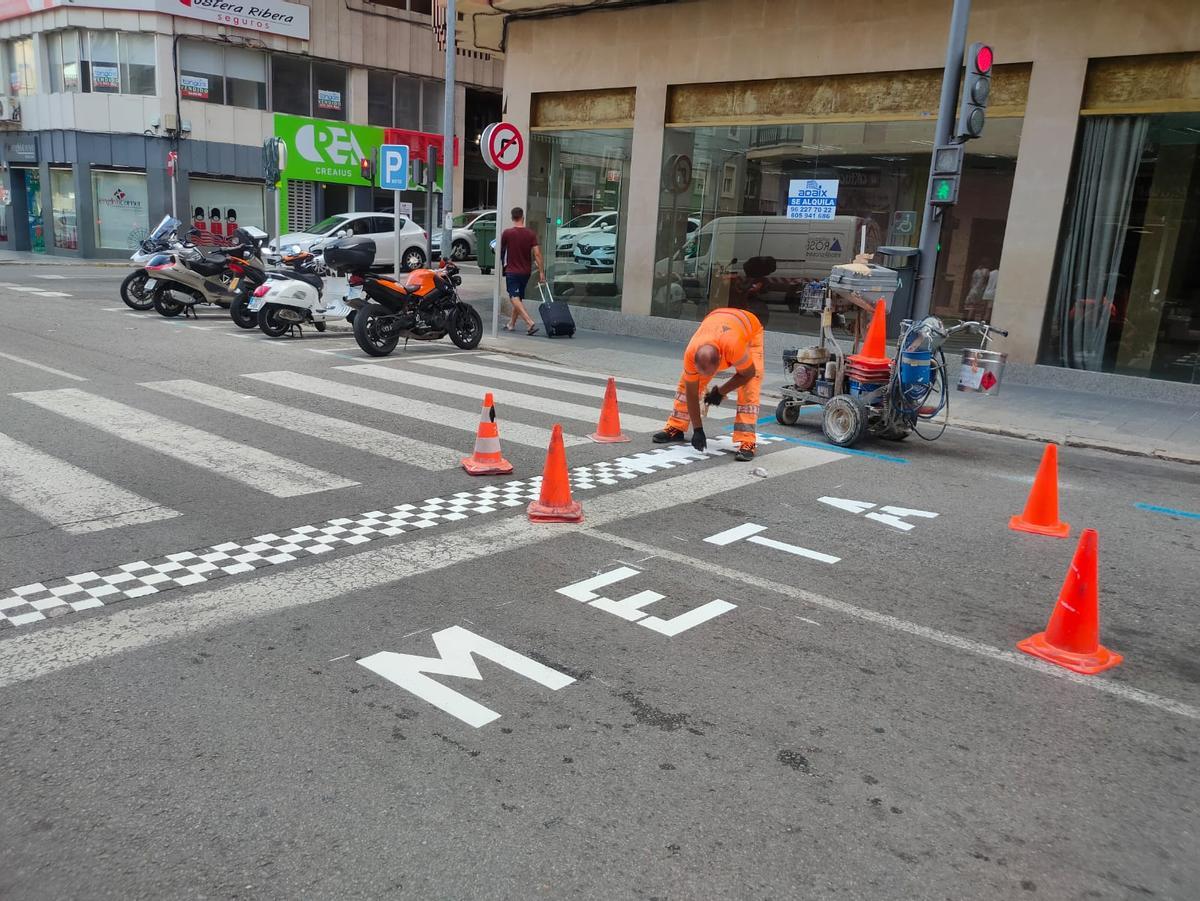 Operarios pintando la línea de meta de la carrera de Xàtiva.