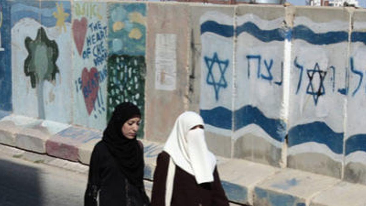 Mujeres palestinas pasan por delante de un graffiti que dice: "Jerusalén siempre será hebreo".