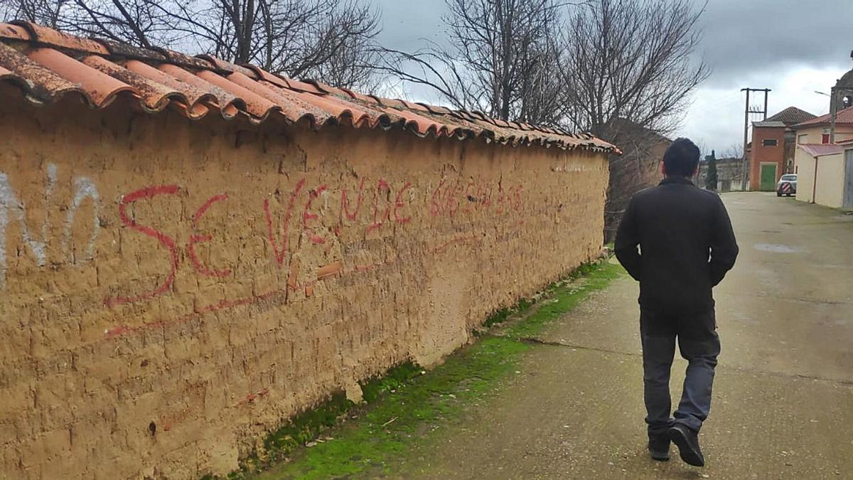 Un vecino de Morales de Valverde camina junto al tapial de una propiedad en venta en la localidad.