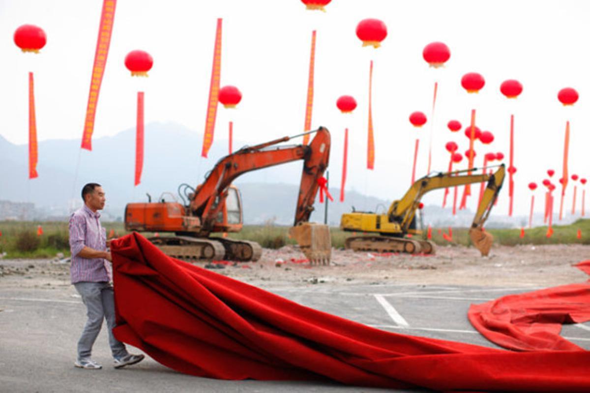 Un home recull una alfombra vermella després de la inauguració d’un edifici a Wenzhou (Xina).