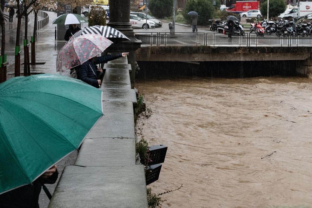 Varias personas observan la crecida del río Onyar, a su paso por el centro de la ciudad de Girona.