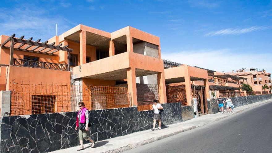 Varios turistas caminan por delante de un complejo de apartamentos inacabados en El Castillo.