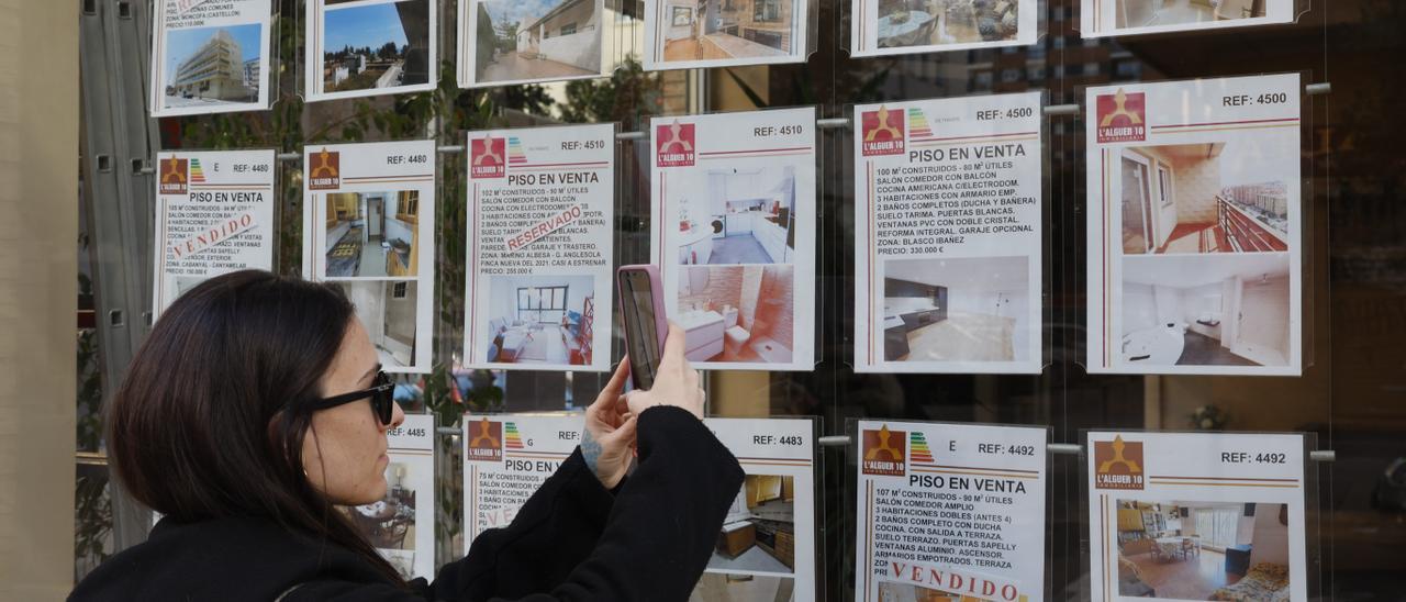 Una joven captura con su móvil la imagen de la oferta de una inmobiliaria de València, ayer.