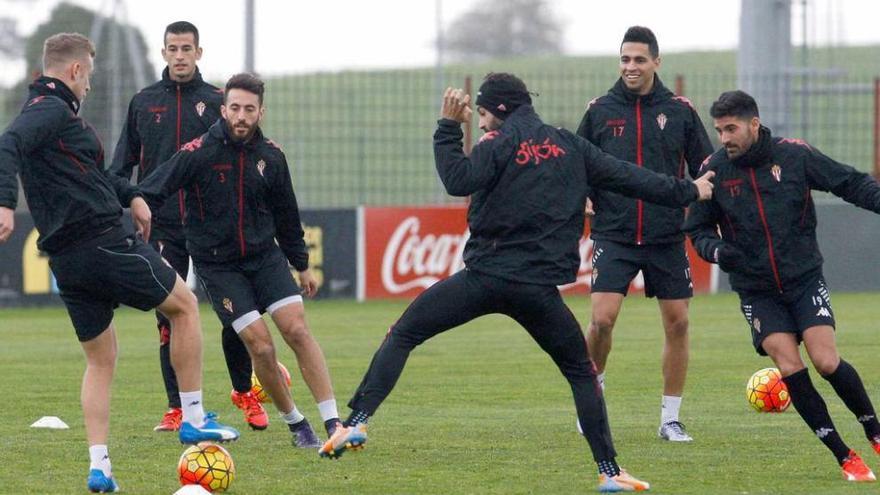 Álex Barrera pisa el balón observado por sus compañeros.