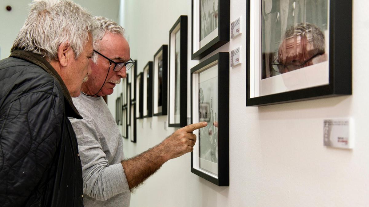 Dos hombres observan una de las fotografías de la muestra.