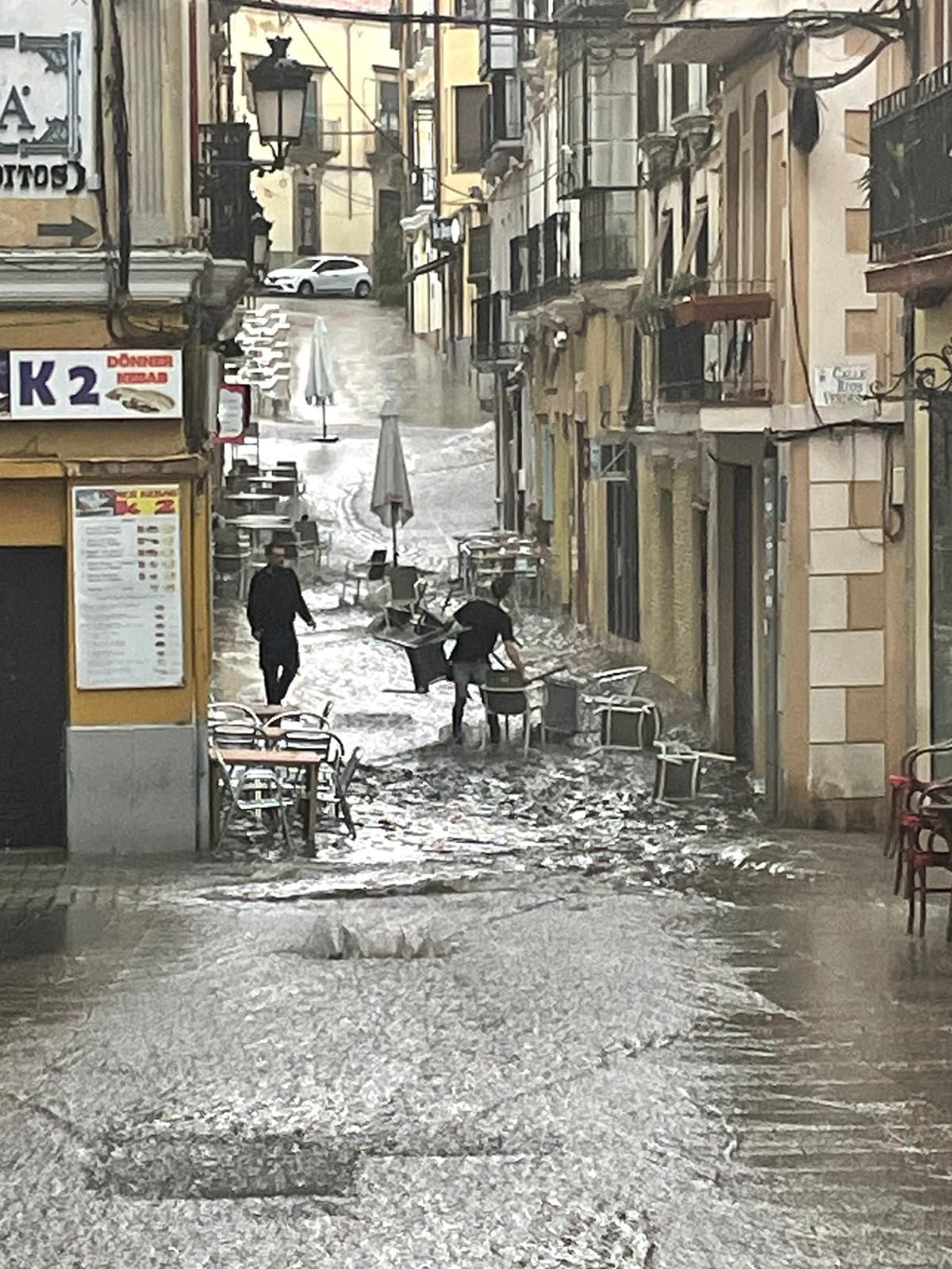 Camareros de la tapería Los Ibéricos, situada en Moret, recogiendo el mobiliario de su terraza arrastrada por el agua hasta la calle General Esponda, casi en la Plaza Mayor