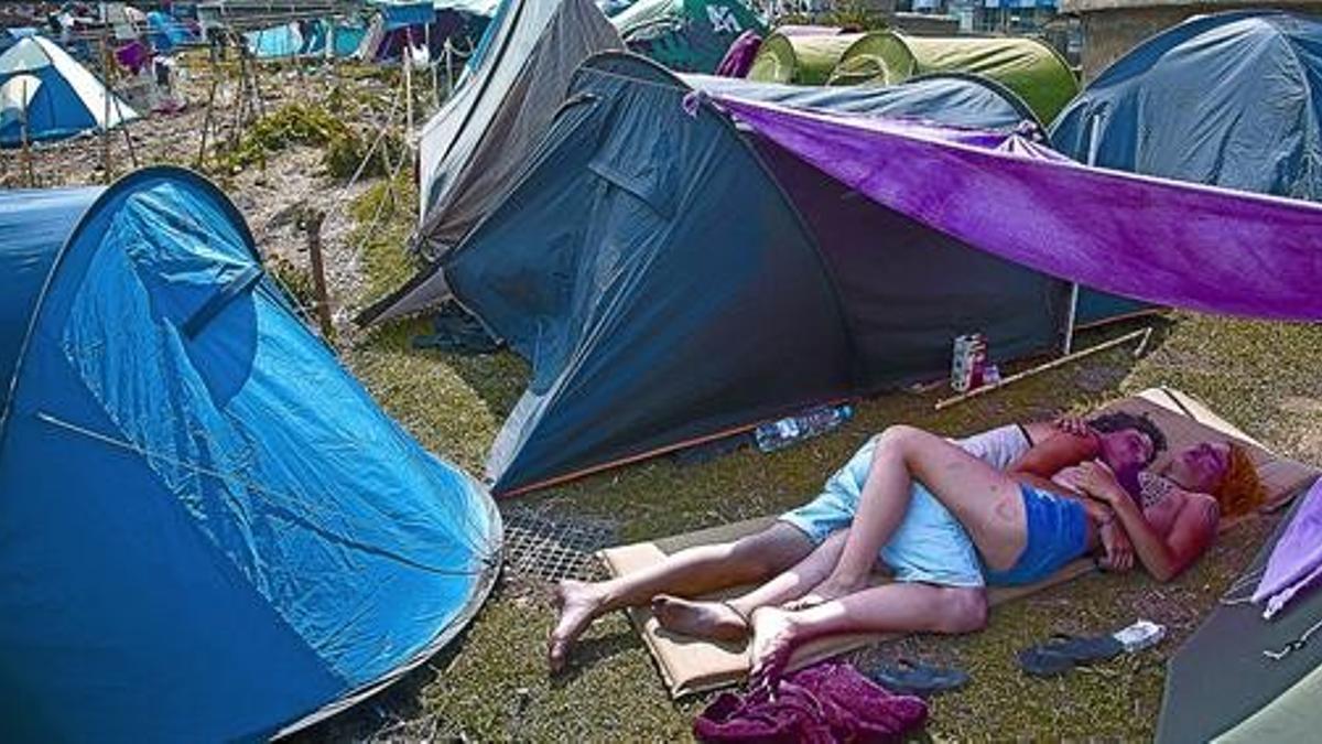 Dos jóvenes acampados en la plaza de Catalunya descansan debajo de un toldo, ayer.