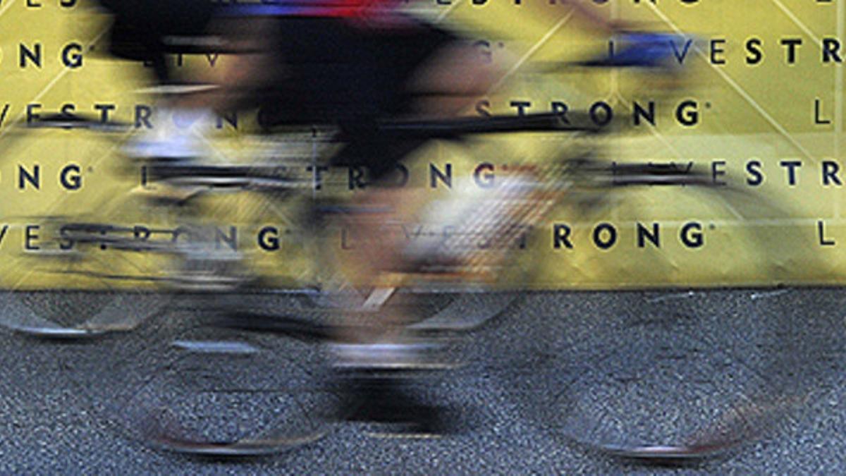 Varios ciclistas ruedan junto a un cartel de Livestrong, la fundación contra el cáncer creada por Armstrong, en Austin (Tejas)