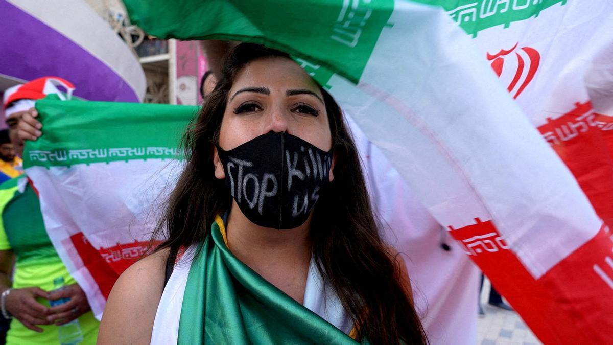 Una mujer con una máscara con un mensaje que dice &quot;dejad de matarnos&quot; tras el partido Gales contra Irán, en Qatar.