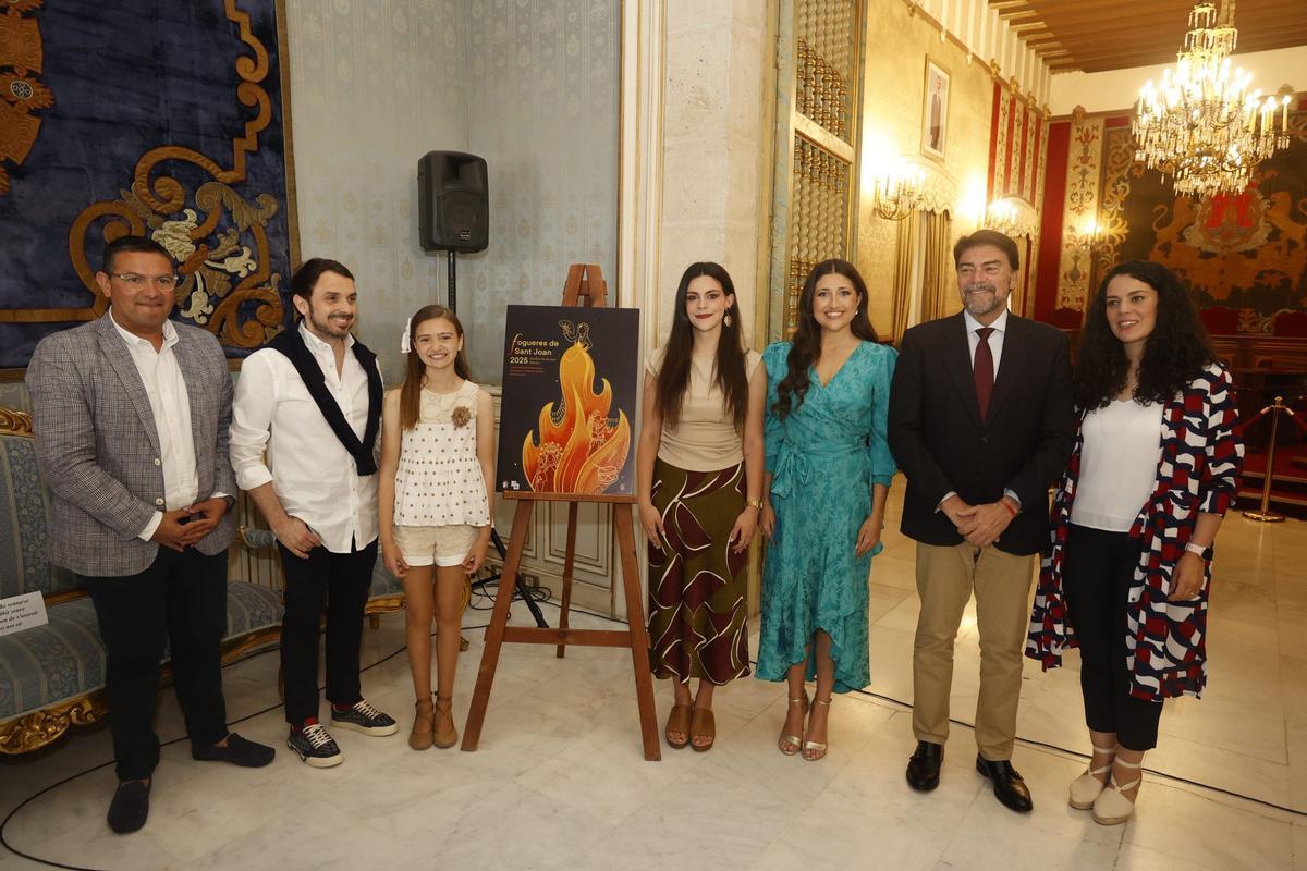 David Olivares, presidente de la Federació de Fogueres; Rubén Hernández, pregonero de las Hogueras 2025; Valentina Tárrega, Bellea del Foc infantil; Sofía Escolano, autora del cartel oficial; Adriana Vico, Bellea del Foc; Luis Barcala, alcalde de Alicante; y Crsitina Cutanda, concejala de Fiestas; posan en la presentación oficial.