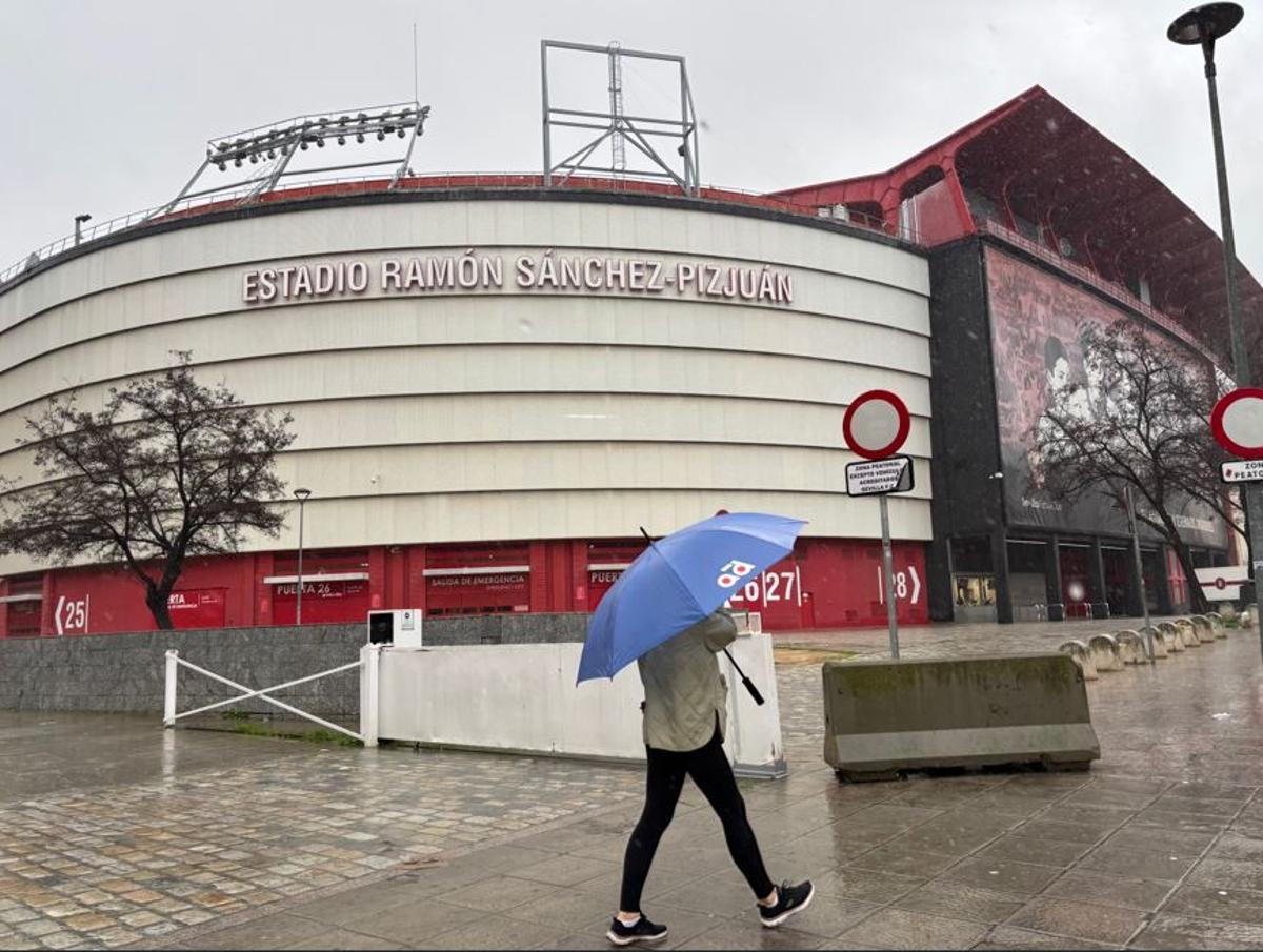 Una persona passeja amb el paraigües davant del Sánchez-Pizjuán.