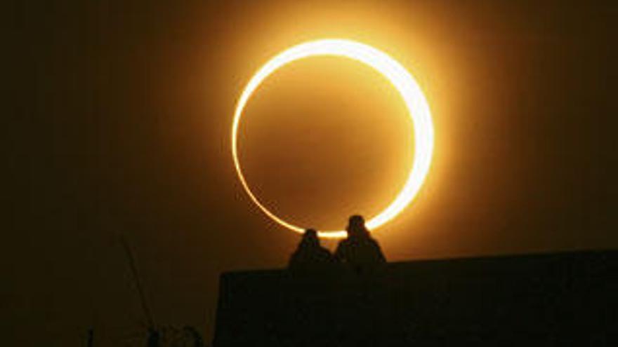 Dos hombres observan el eclipse anular de sol desde un puente en Zhengzhou, en China.