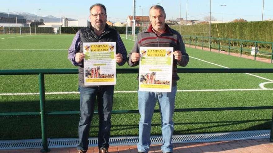 Pedro Riesgo y Carlos Fernández, ayer en el campo de fútbol de El Berrón, con los carteles de la campaña.