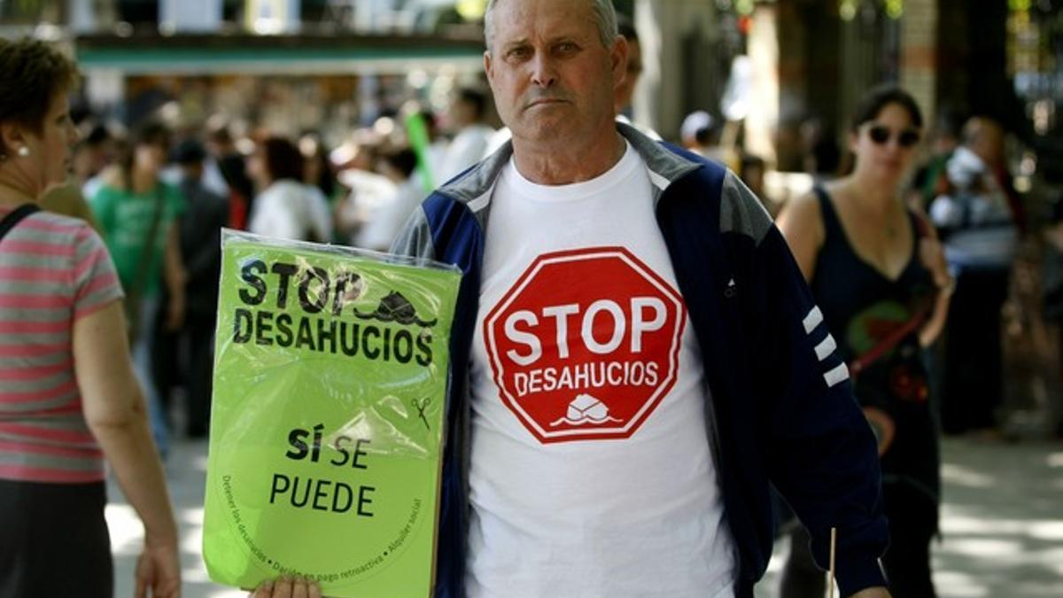 Un manifestante muestra una pancarta contra los desahucios, este domingo en Madrid.