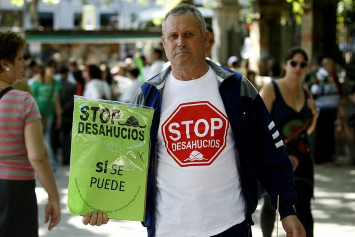 Un manifestante muestra una pancarta contra los desahucios, este domingo en Madrid.