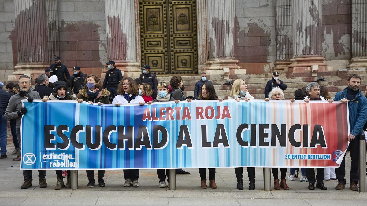 Demonstranten stehen während einer Protestaktion der Gruppe «Rebelion cientifica» vor dem Madrider Parlament mit einem Transparent mit der Aufschrift &quot;Roter Alarm. Hört auf die Wissenschaft zu&quot;. Die Demonstranten, Wissenschaftler, bewarfen das Parlamentsgebäude mit roter Farbe, um die Untätigkeit der Regierungen in Sachen Klimawandel anzuprangern.