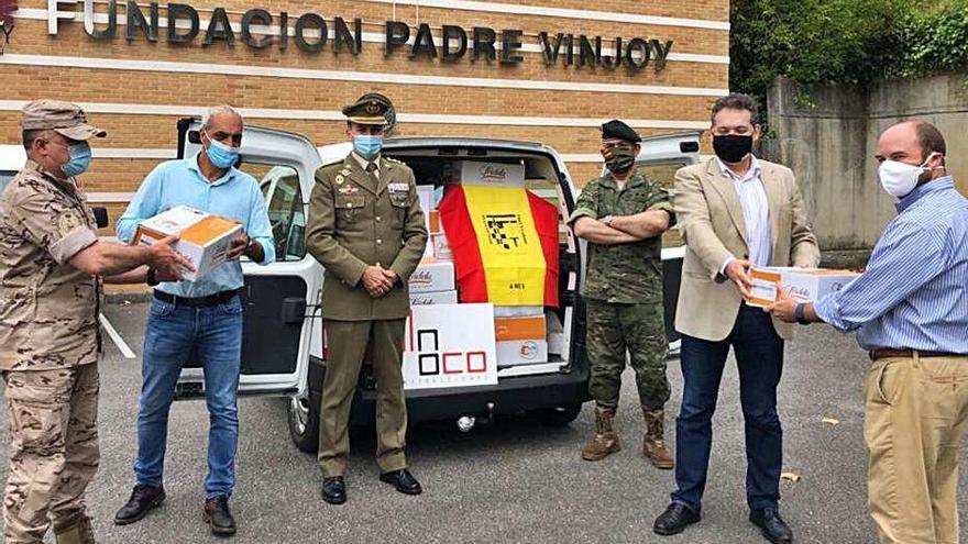 A la derecha, Enrique Somolinos entrega una caja de croquetas al director de la Fundación Vinjoy, Adolfo Rivas, junto a varios reservistas.