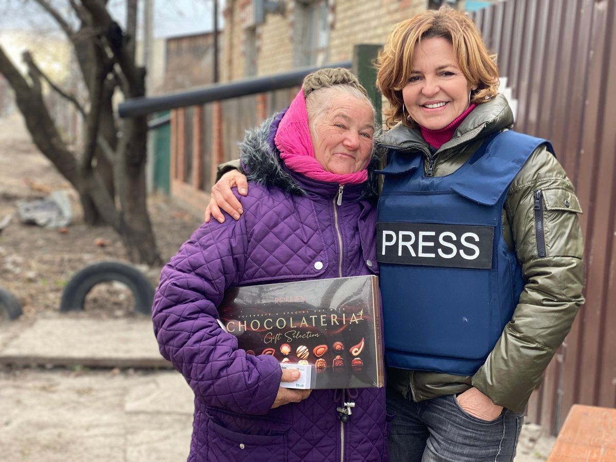 Aludena Ariza, con el chaleco que la acredita como periodista, abraza a una vecina en Bucha, Ucrania.