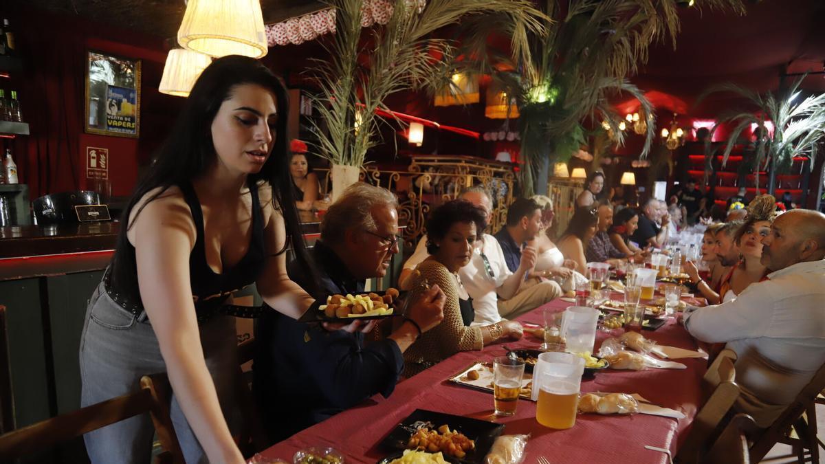 Una camarera atiende una mesa en una caseta de la Feria de Córdoba durante las comidas.