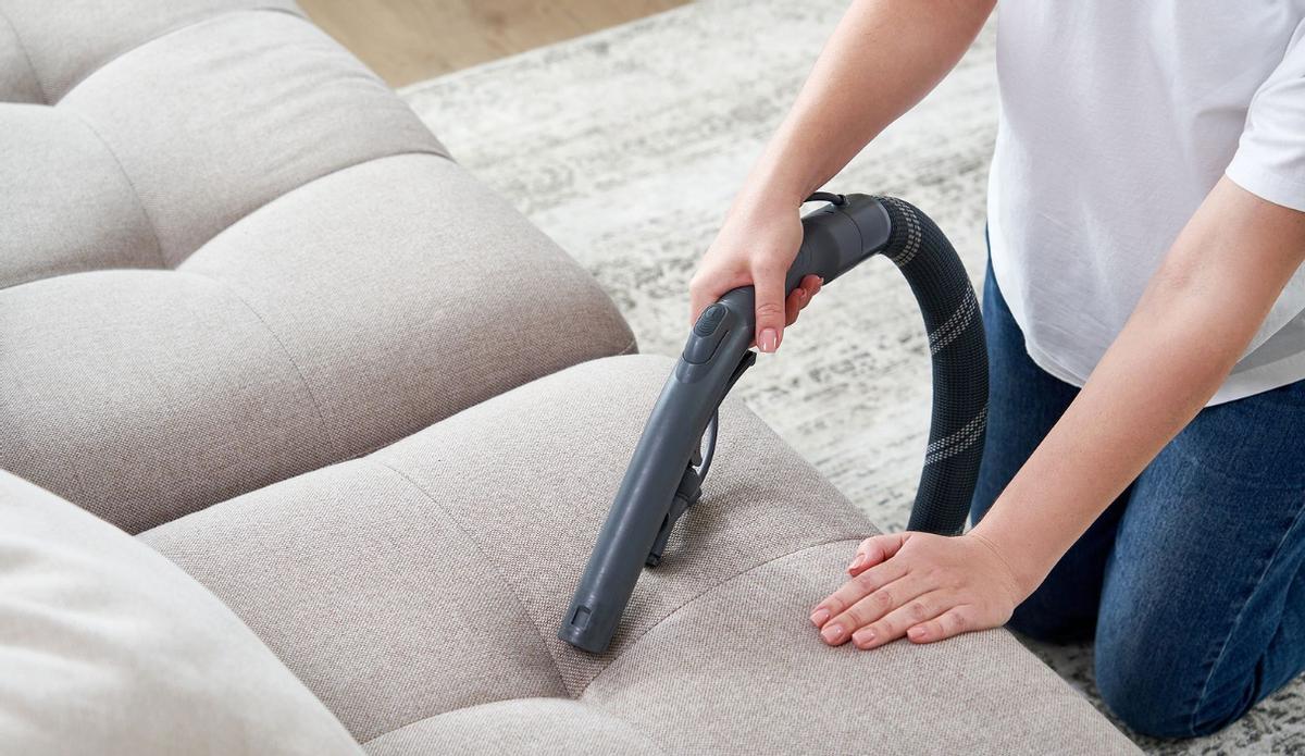 Quitar la suciedad del sofá con limpiador de tapicería, primer plano.