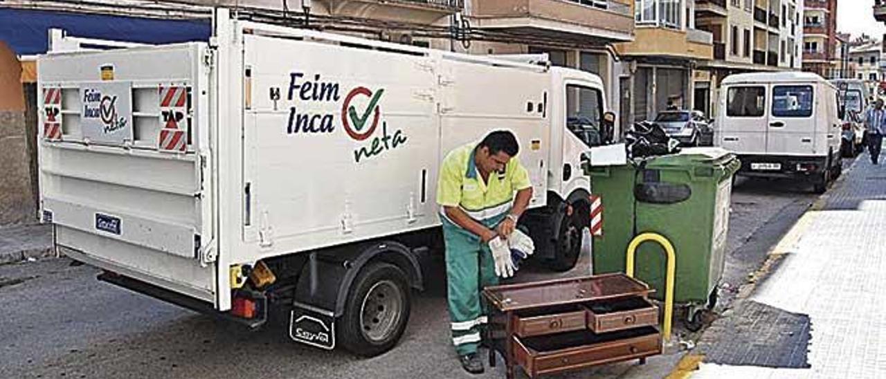 Un oparario recoge voluminosos de un contenedor en Inca.