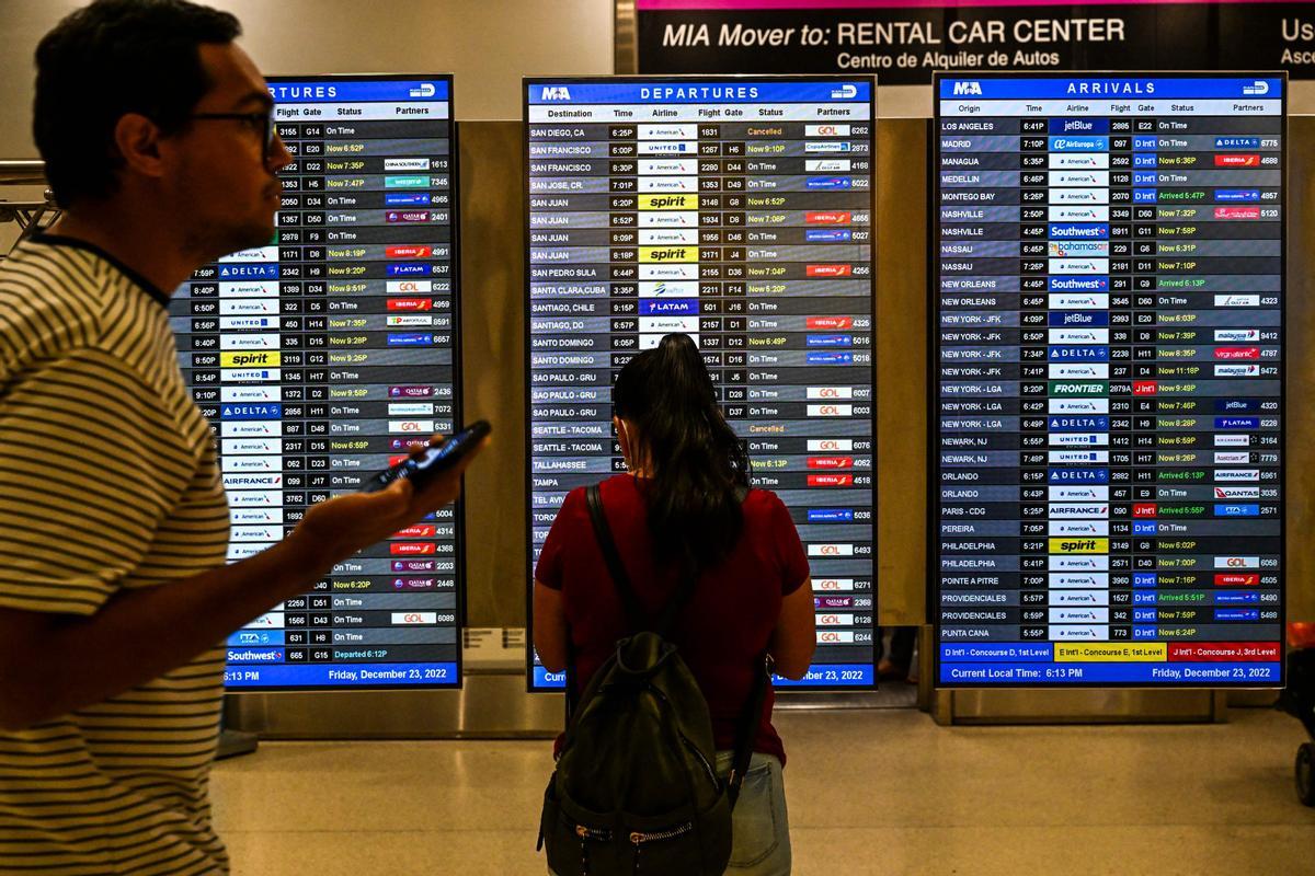 Viajeros miran las pantallas del aeropuerto intenacional de Miami para comprobar las afectaciones en los vuelos debido a la tormenta Elliott.