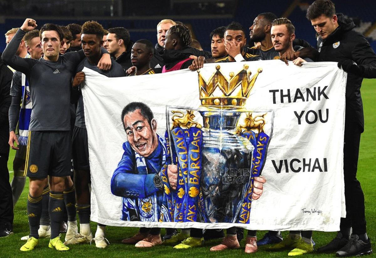 Los jugadores del Leicester City James Maddison (2R) y Demarai Grey (3L) sostienen una pancarta que muestra al presidente, Vichai Srivaddhanaprabha, después del partido de fútbol de la Premier League inglesa entre Cardiff City y Leicester City.