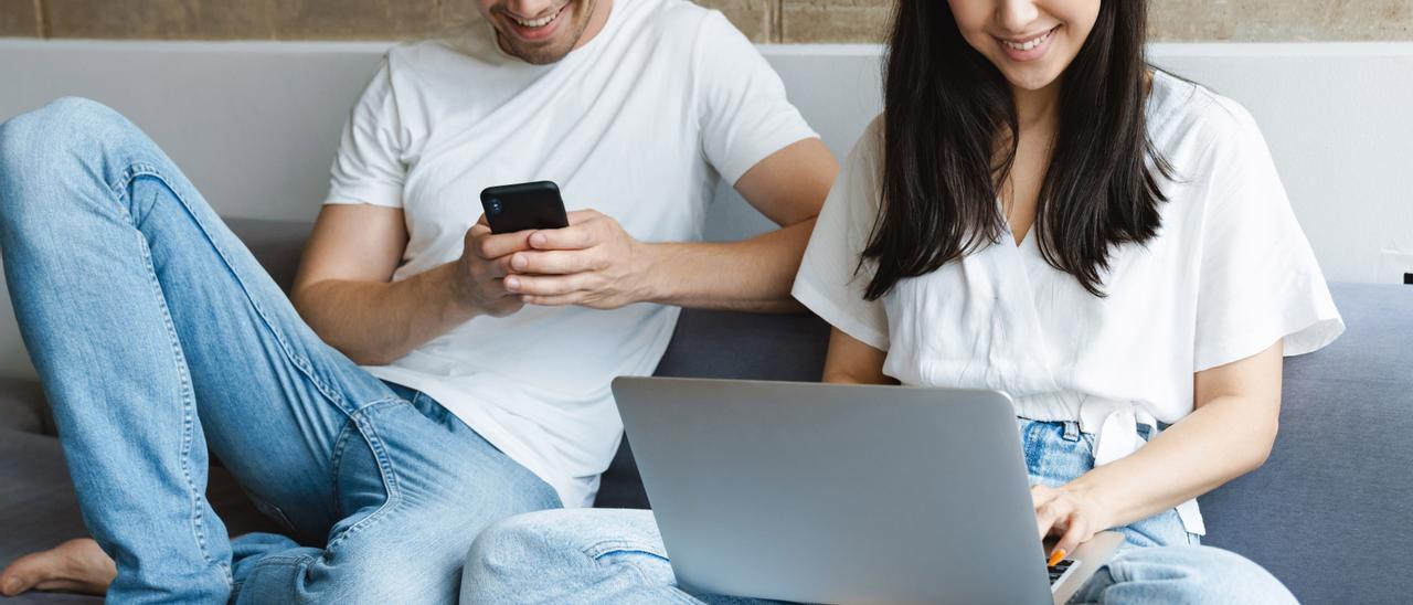 Dos jóvenes se conectan a Internet desde su móvil y su ordenador portátil