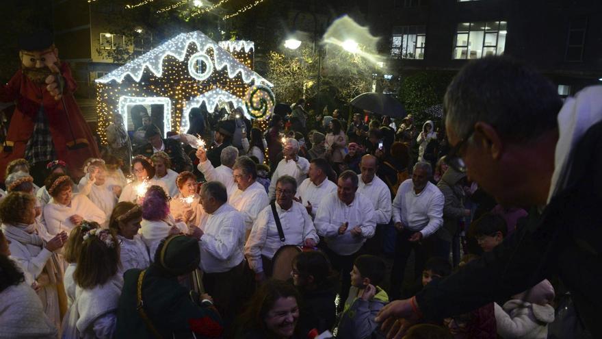 La alcaldesa de Cangas (parte inferior) enciende las luces en la Praza do Concello junto al Apalpador gigante, Gaiteiros y Máis Cantos.|
