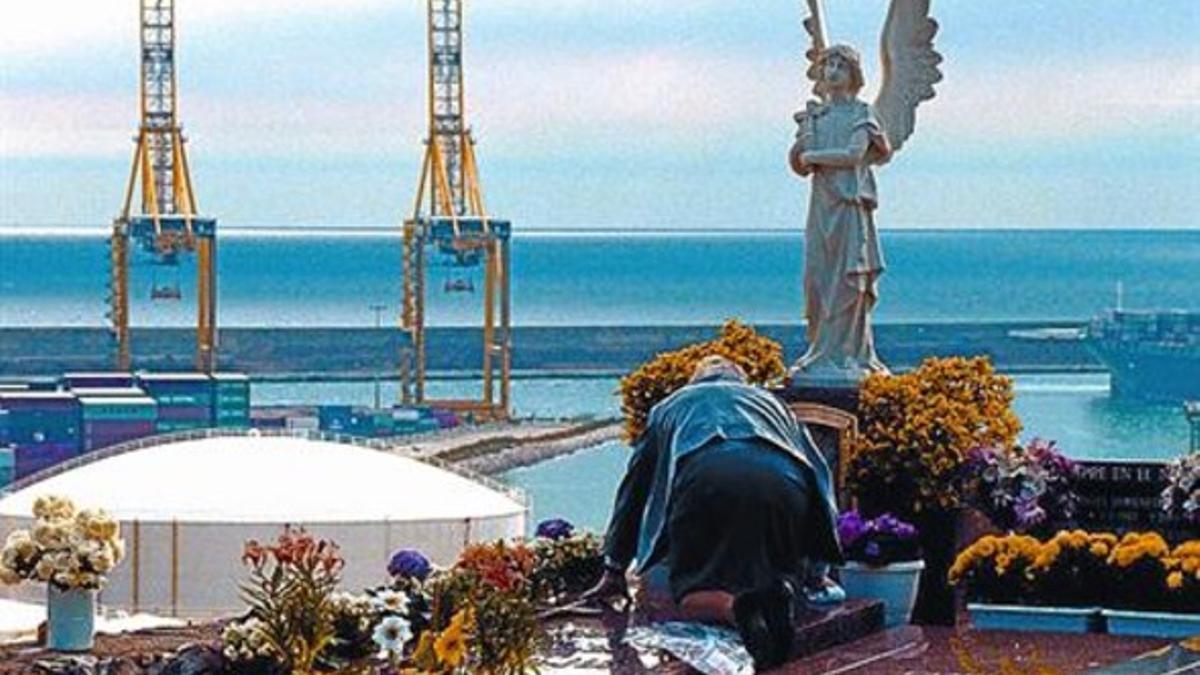 Un hombre reza junto a una sepultura en el cementerio de Montjuïc.