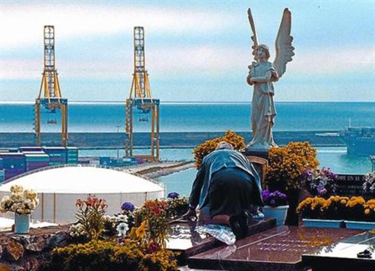 Un home resa davant una sepultura al cementiri de Montjuïc. Un home resa davant una sepultura al cementiri de Montjuïc.