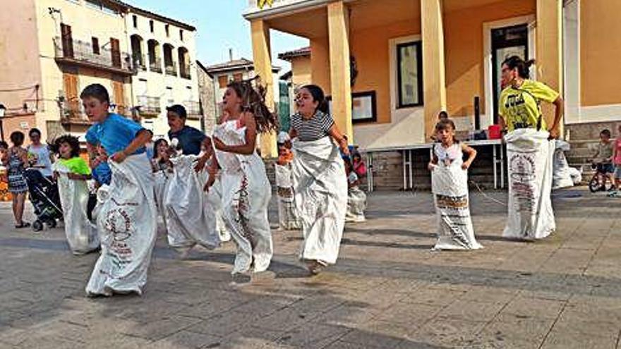 Els infants, juntament amb la responsable de Rural Salut, fent una cursa de sacs a la plaça de la Vila