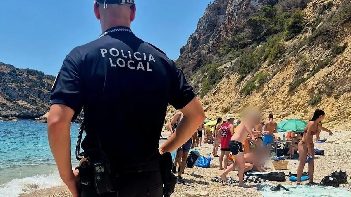Un agente vigila que los bañistas recojan sus cosas y se marchen de la cala clausurada.