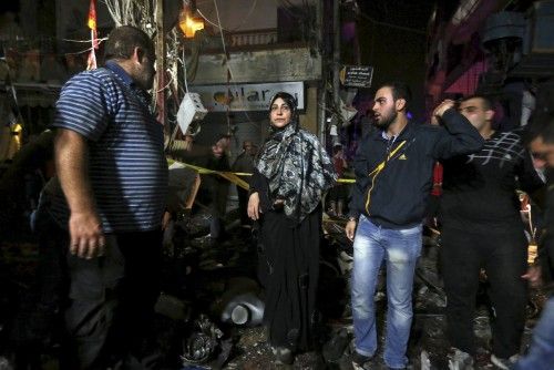 Residents inspect a damaged area caused by two explosions in Beirut's southern suburbs, Lebanon