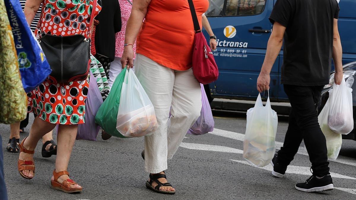 Consumidores con bolsas de plástico de asas.