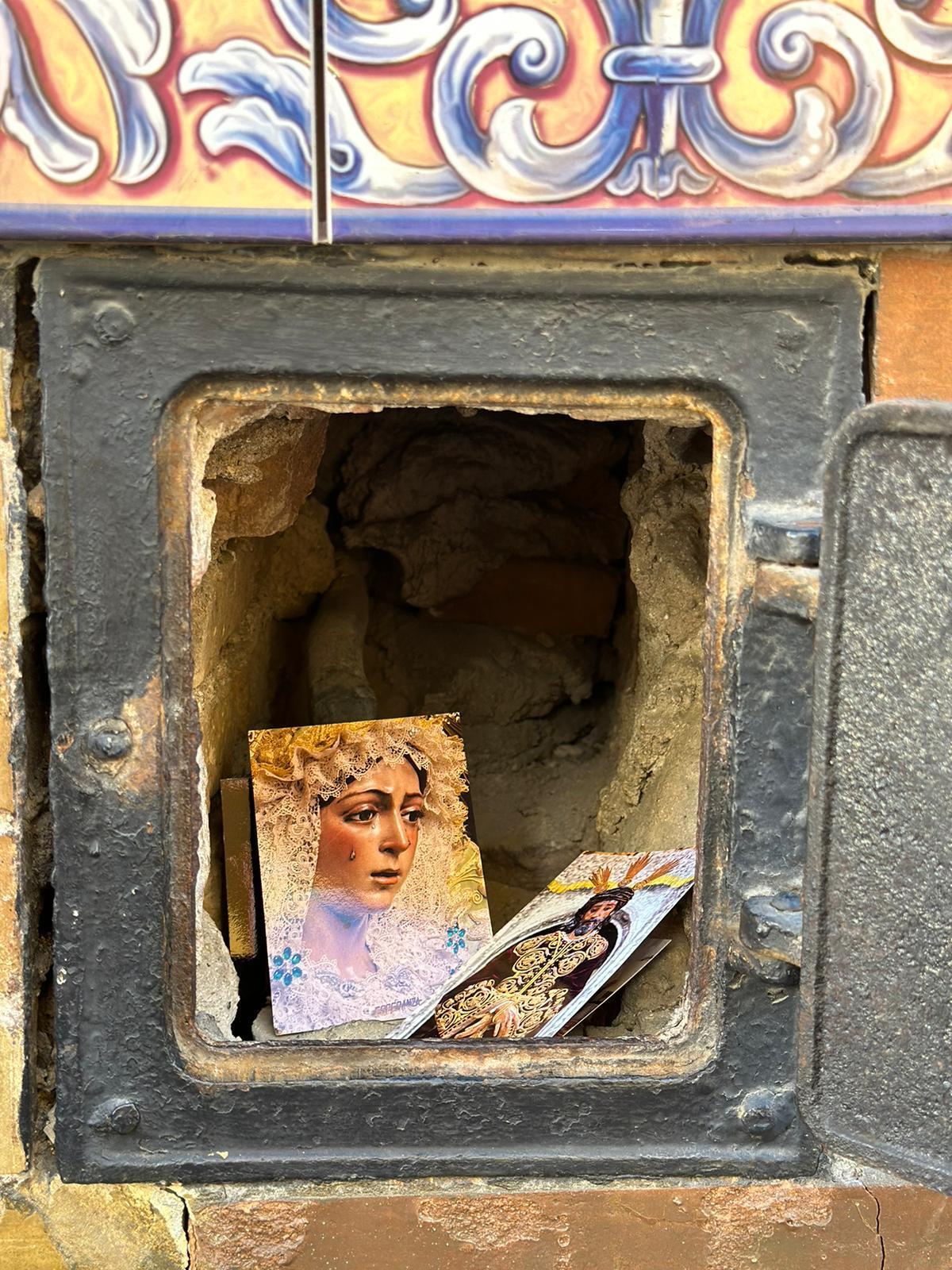 Estampitas de la Virgen Esperanza Macarena y el Señor de la Sentencia en el interior del registro del agua de la calle San Luis.