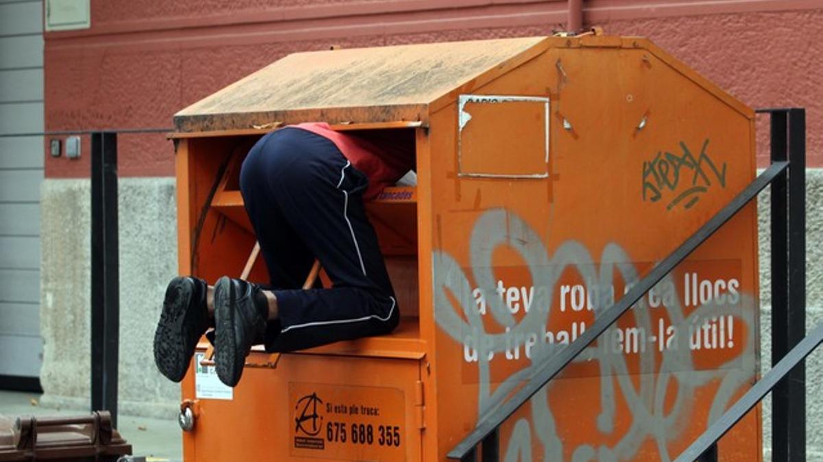 Un hombre rebusca dentro del contenedor de una oenegé.