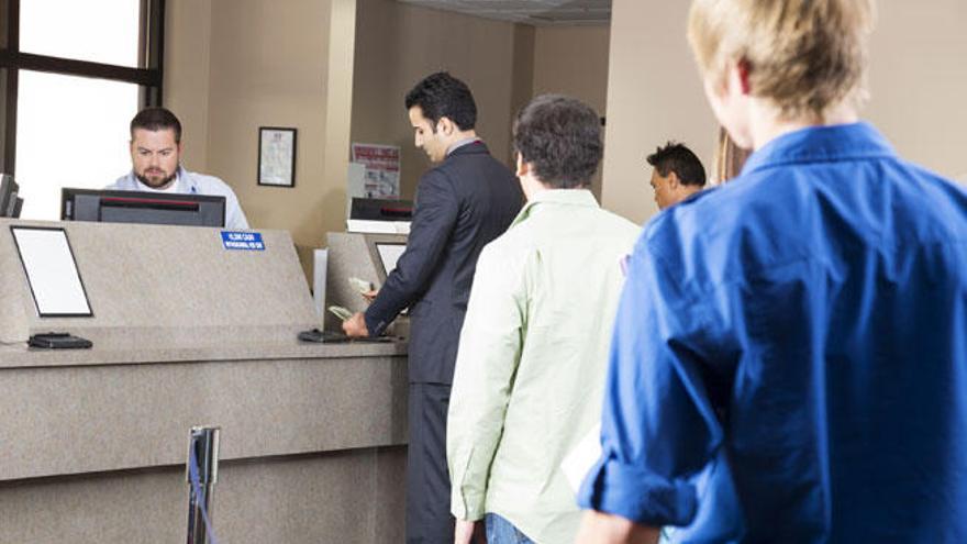 Varios clientes hacen cola en un banco.